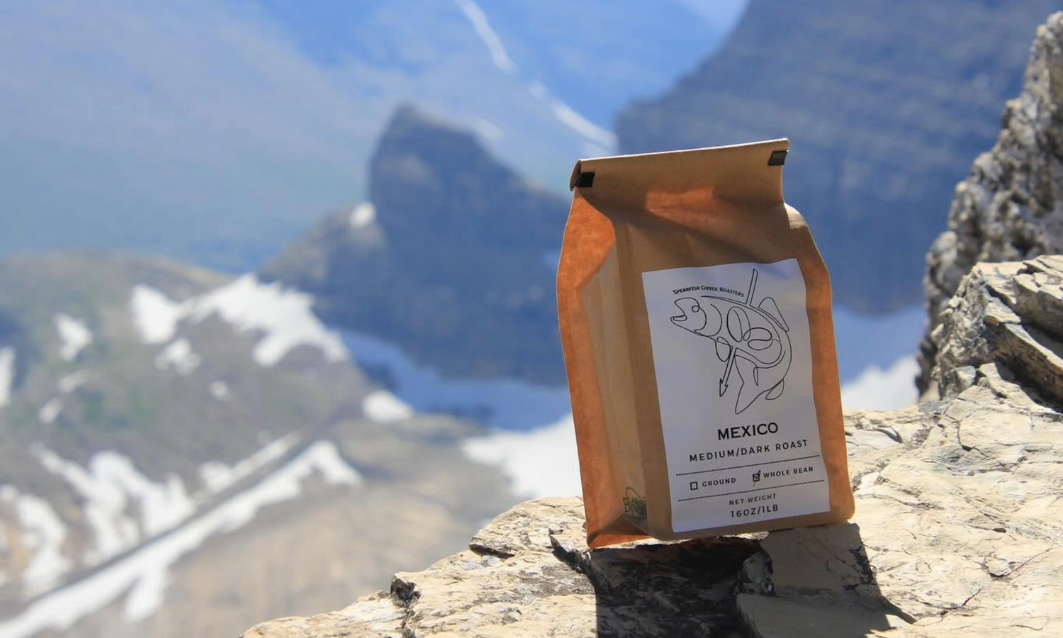 Spearfish Coffee Roasters Mexico Medium-Dark roast Whole Bean Coffee on Edge of Cliff with Scenic Mountain Backdrop